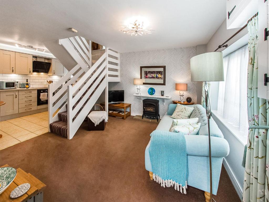 a living room with a blue couch and stairs at Apple Blossom Cottage - Uk46648 in Cheddar