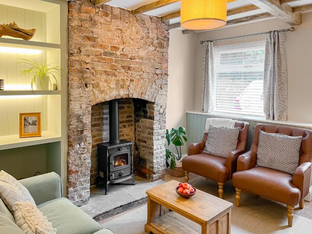 a living room with a brick fireplace and leather chairs at Cosy Cottage in Howden