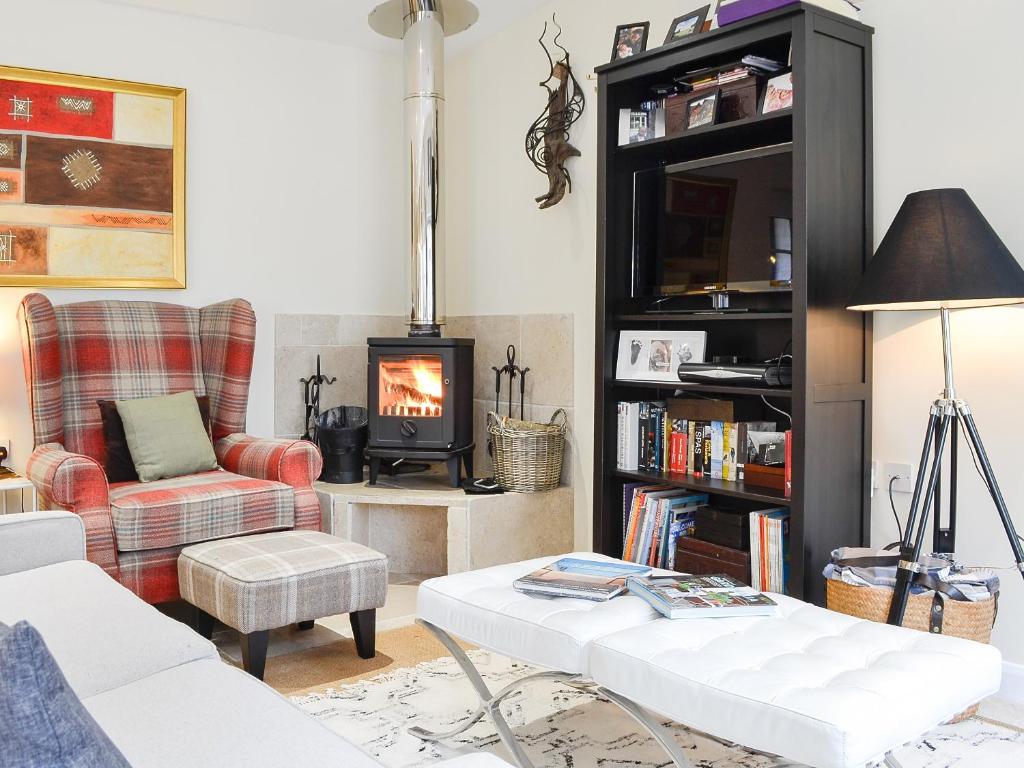 sala de estar con sofá, silla y chimenea en Fairylea Cottage, en Rosemount