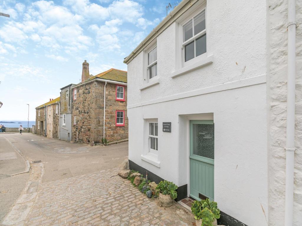 a white building with a green door on a street at Fishermans Cottage in St Ives