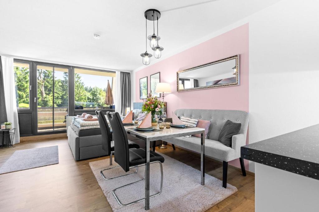a dining room and living room with a table and chairs at Ferienwohnung Harmonie mit Pool und Fitness in Sankt Englmar