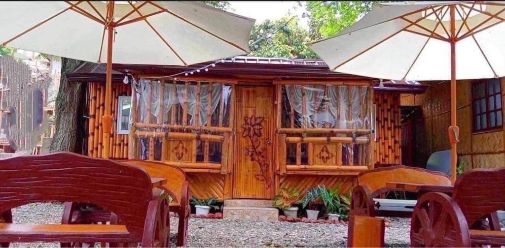 a wooden house with two umbrellas and tables and chairs at Sea-Sky Blue Beach Resort at Malabrigo Lobo Batangas-TW in Lobo