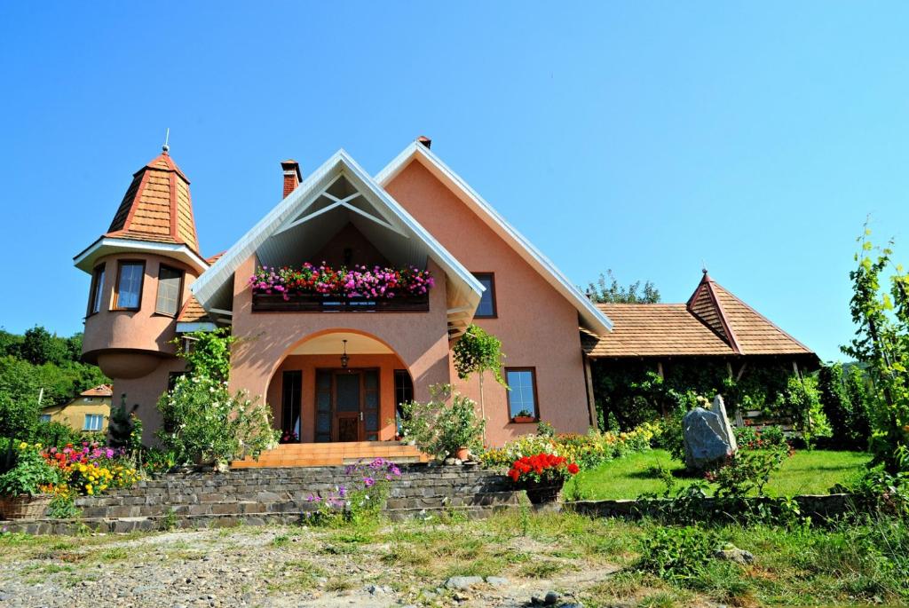 uma casa com uma torre e flores no quintal em Polychko Winehouse em Vynohradiv