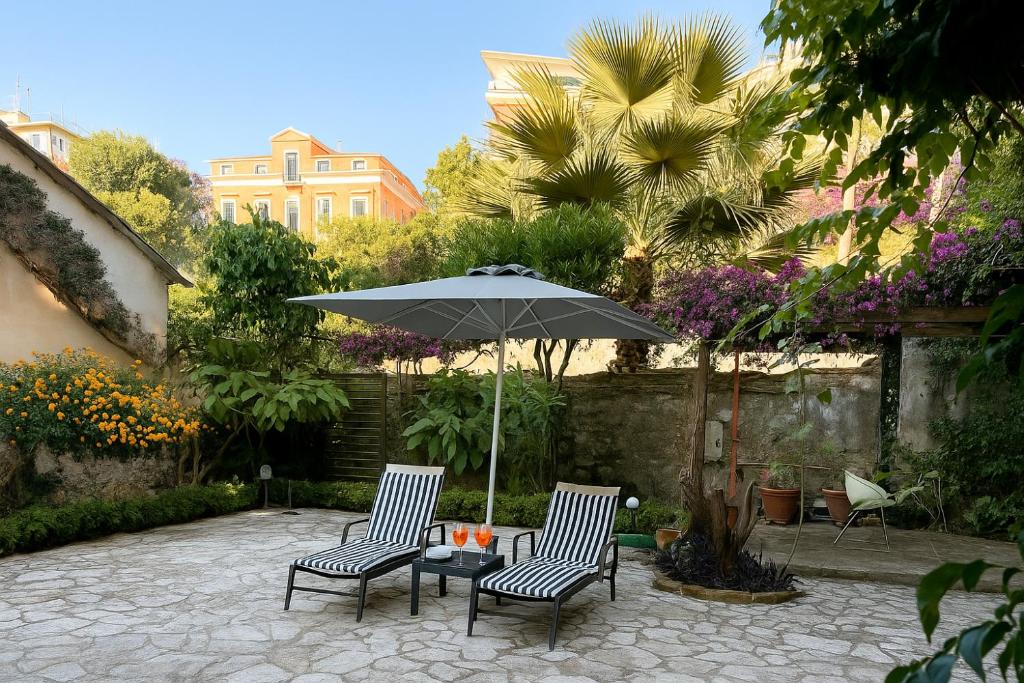 a patio with two chairs and a table with an umbrella at Verdant Escape Corfu in Corfu