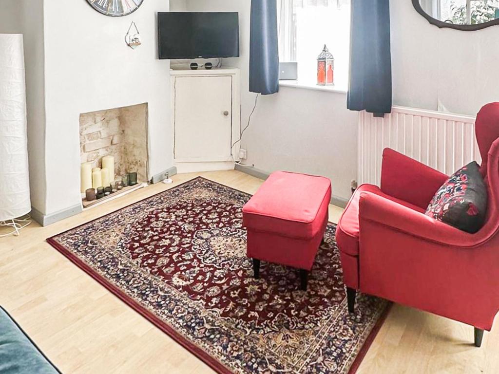 ein Wohnzimmer mit einem roten Stuhl und einem Kamin in der Unterkunft Kathali Cottage in Exmouth