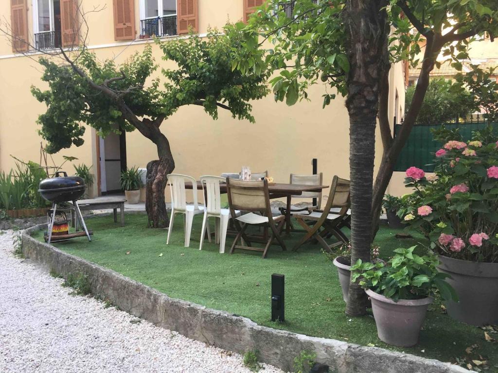 un patio avec une table, des chaises et des arbres dans l'établissement Night at La Niçoise - 6 per, à Nice