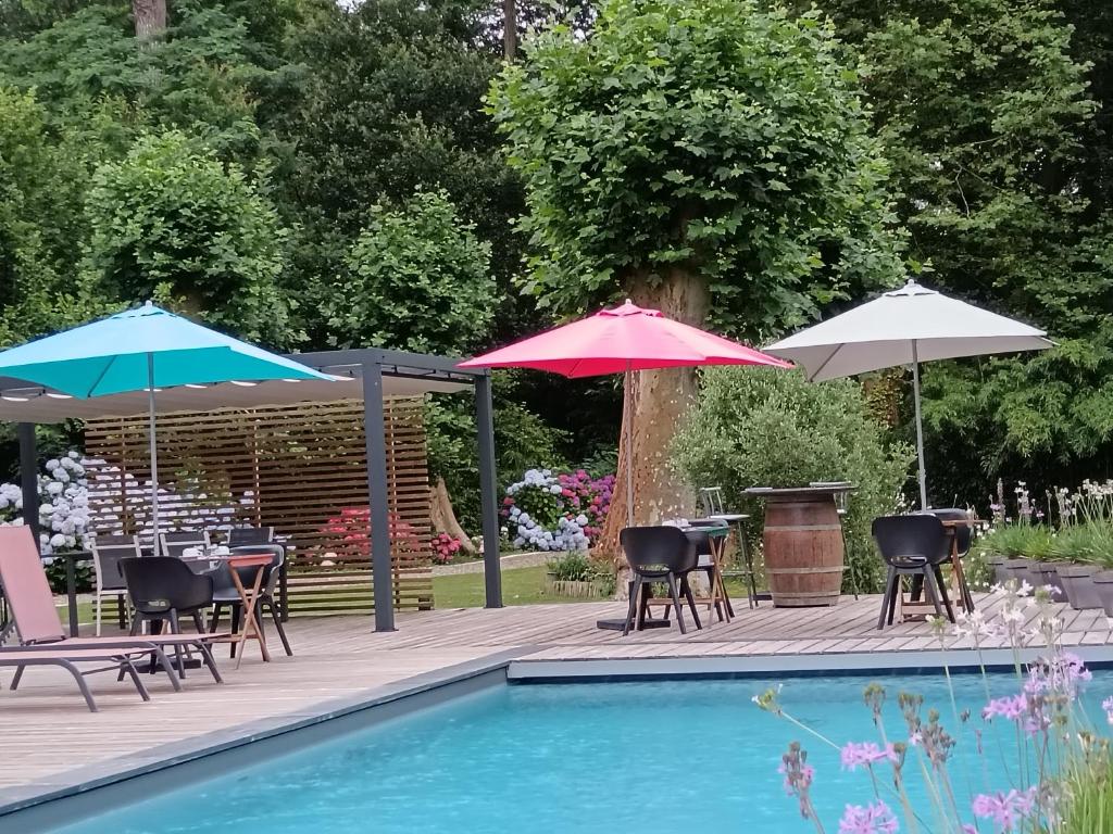 una piscina con sombrillas y sillas y una mesa con sillas y mesas. en Le Moulin de Saubrigues, en Saubrigues