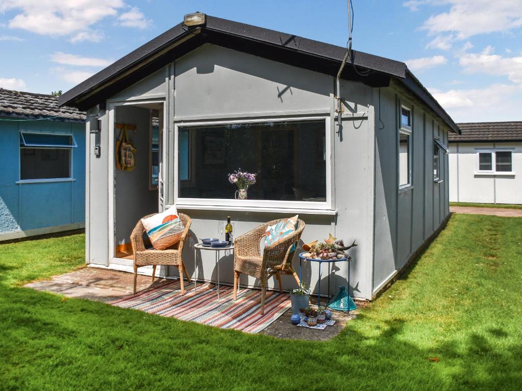 a shed with two chairs and a table in a yard at Seaglass Chalet - Uk47636 in Mundesley