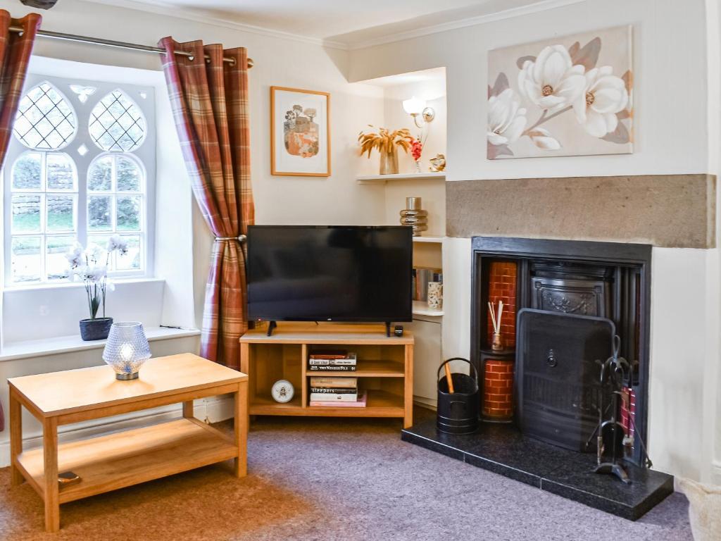a living room with a television and a fireplace at Woodbine Cottage in Whittington