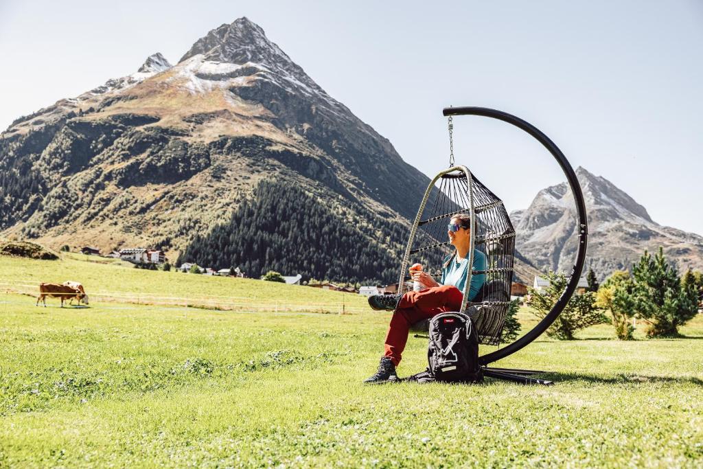a man sitting in a tire swing in a field at Apart Zimalis in Galtür