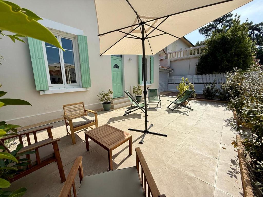 un patio avec une table, des chaises et un parasol dans l'établissement Charmante maison pour 6 personnes à 200m de la plage, à Saint-Palais-sur-Mer