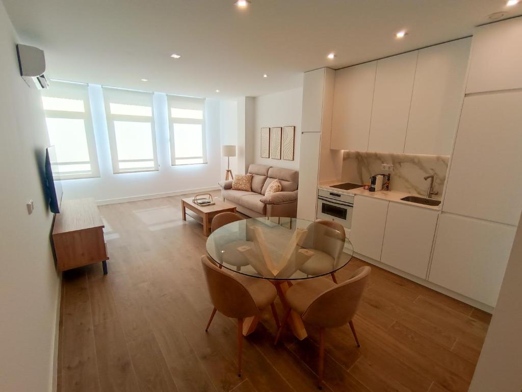 a kitchen and a living room with a glass table at Apartamentos DALA in Madrid