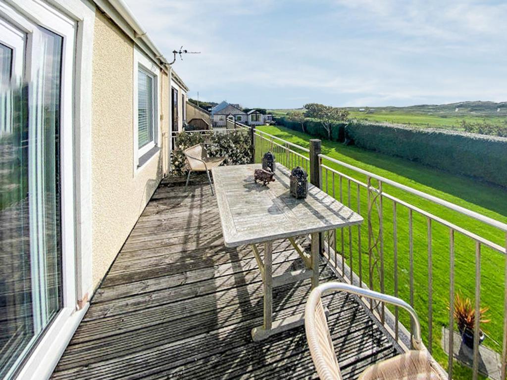 una terrazza in legno con tavolo e sedie sul balcone. di Mill Cottage ad Aberdyfi