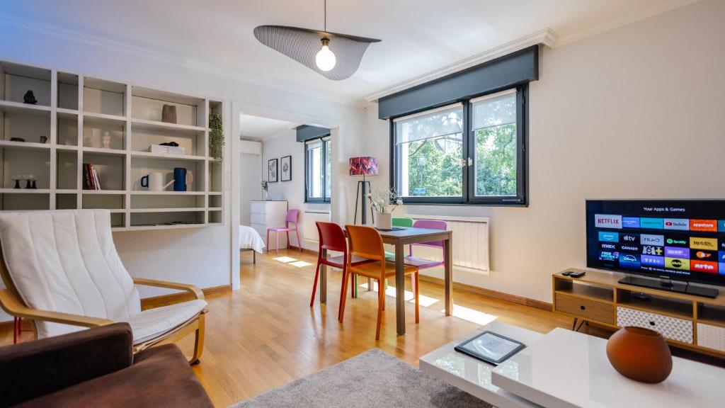 un salon avec une table et une télévision dans l'établissement Les Alisiers - 3 pièces - climatisé, à Strasbourg