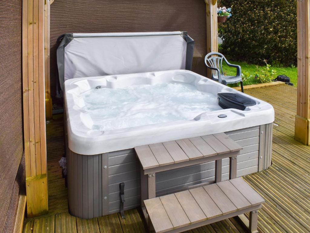 a hot tub sitting on a deck with a chair at Pineville in Dover