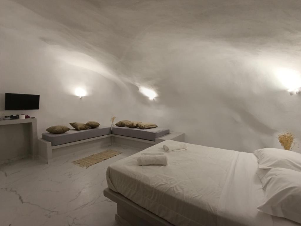 a white bedroom with a bed and a couch at Santorini White Lotus in Perissa
