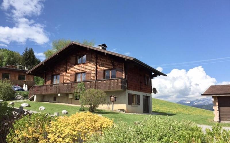 une grande maison en bois sur une colline avec une cour dans l'établissement All-wood chalet in Haute-Savoie, à Nancy-sur-Cluses
