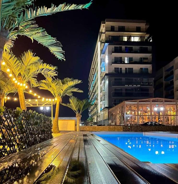 a pool at night with palm trees and a building at Yvo 18 by Signature in Mamaia Sat/Năvodari