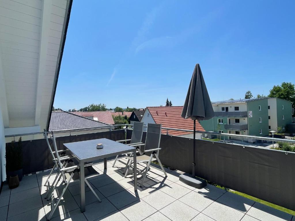 a table and chairs on a balcony with an umbrella at Schlossseeapartment in Salem