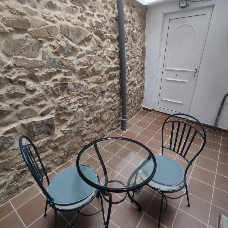 2 sillas y una mesa frente a una pared de piedra en Estudio en Blanes, en Blanes