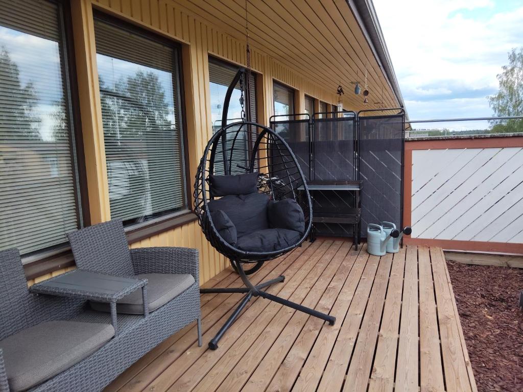 a porch with a swing and two chairs on a deck at Pieksämäellä saunallinen rivitalokaksio in Pieksamaki