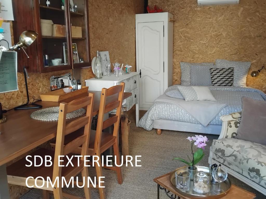 Cette petite chambre comprend un lit, un bureau et une table. dans l'établissement Le laboratoire shabby chic de la parfumerie du manoir, à Chavagne