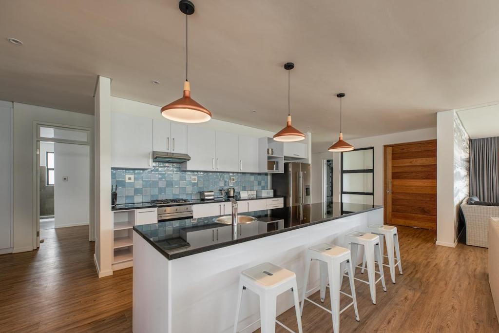 a kitchen with a bar with stools in it at 48 On Possession Island in Swakopmund