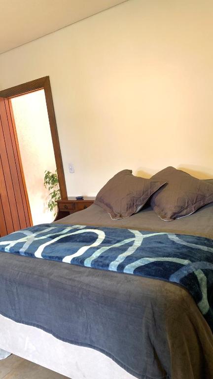 Una cama con una manta azul y blanca encima. en Encanto das Araucárias II, en Campos do Jordão