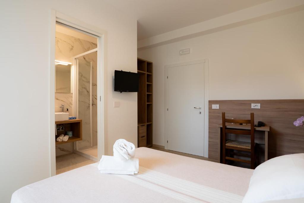 a bedroom with a white bed and a bathroom at Hotel Berna in Eraclea Mare