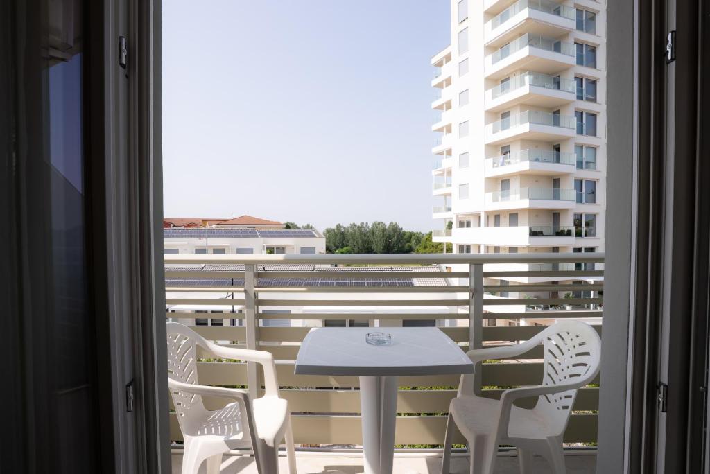 a balcony with a table and chairs and a building at Hotel Berna in Eraclea Mare