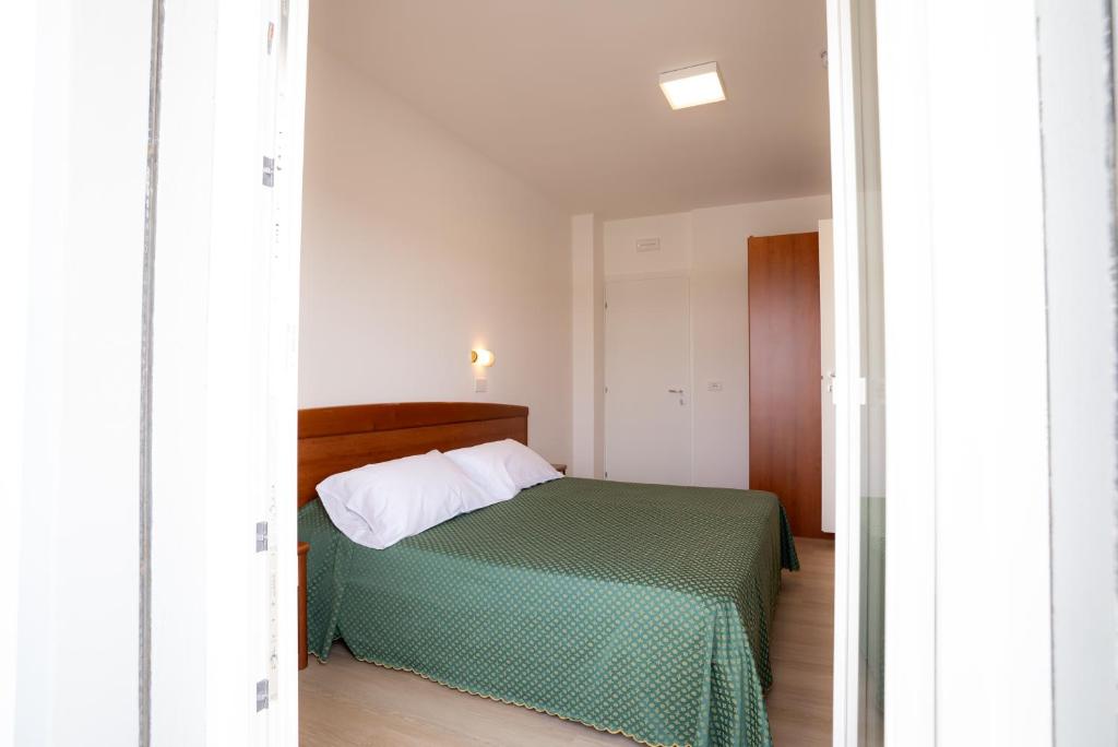 a bedroom with a bed with a green bedspread at Hotel Berna in Eraclea Mare