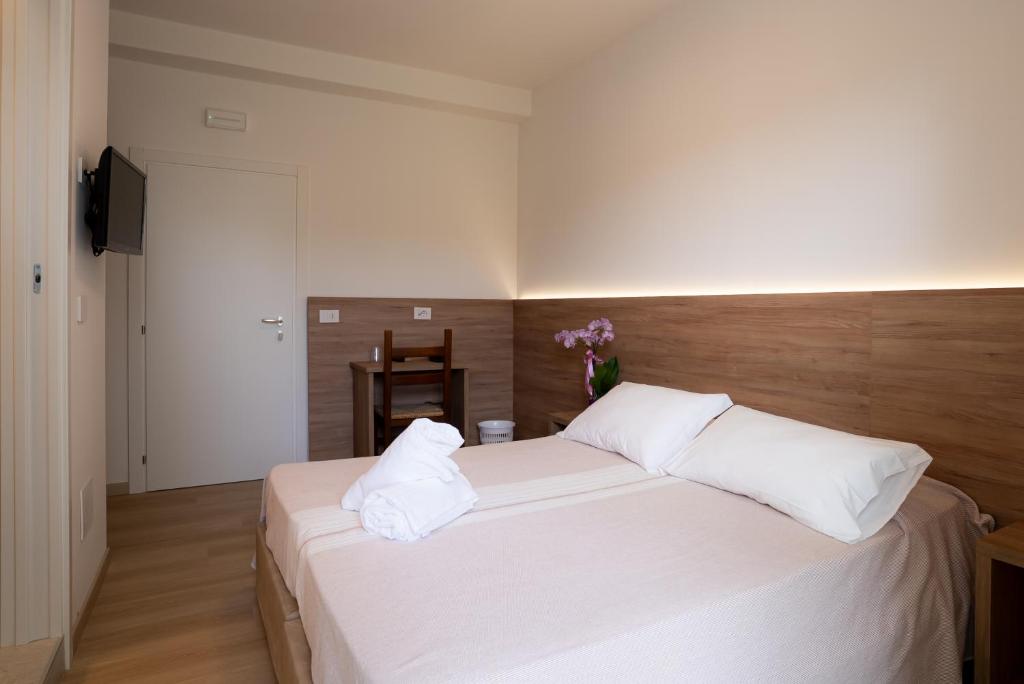 a bedroom with a large bed with white sheets and pillows at Hotel Berna in Eraclea Mare