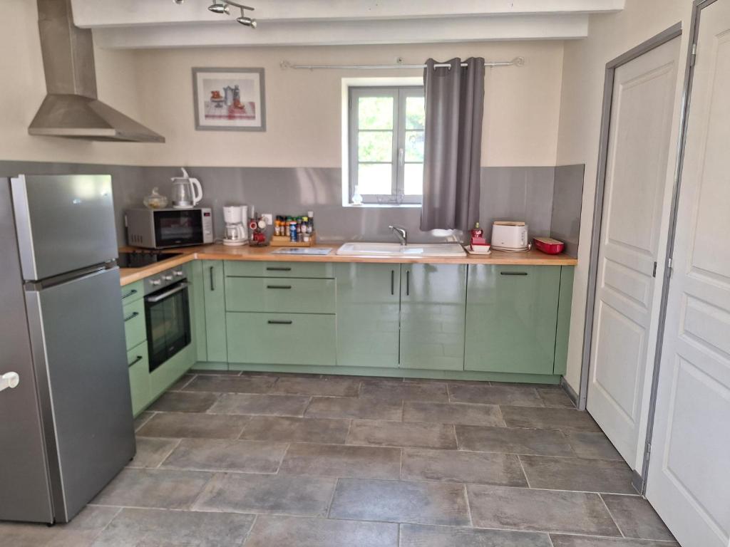 une cuisine avec des armoires vertes et un évier dans l'établissement Cottage au calme avec parking privé, à Lavoux