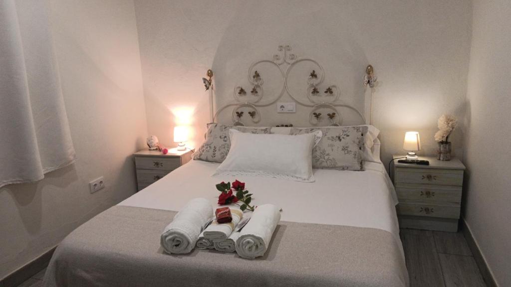 a white bed with two towels and flowers on it at Apts la cañada birding con encanto y patio en monfrague torrejon el Rubio in Torrejón el Rubio
