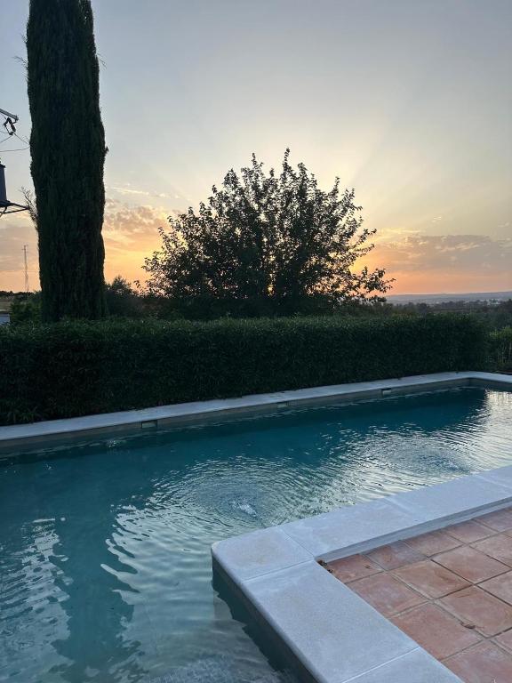 a swimming pool with a sunset in the background at Casa rural La Liñana in Córdoba
