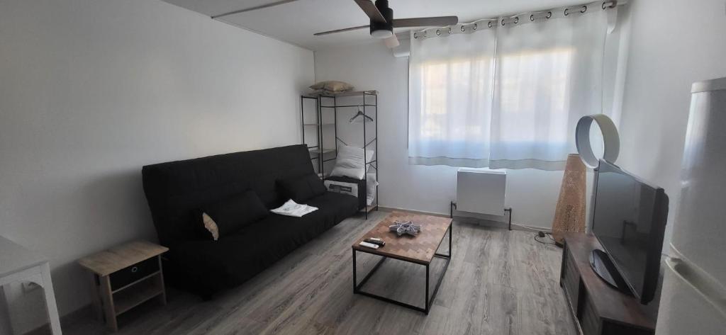 a living room with a black couch and a table at Studio - Cap d'Agde in Cap d'Agde