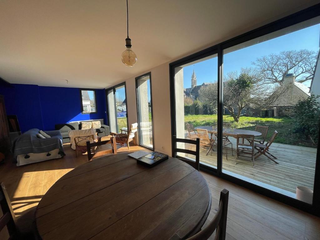 - un salon avec une table en bois et une grande fenêtre dans l'établissement Jolie maison de village proche de la mer, à Clohars-Fouesnant