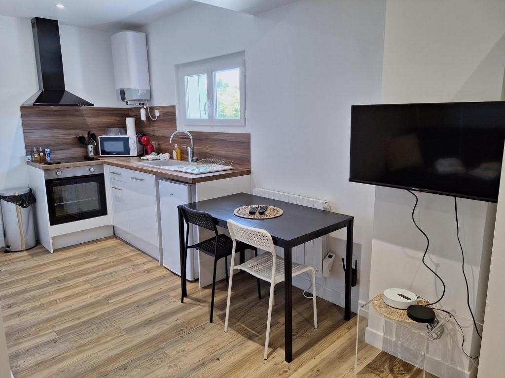una pequeña cocina con mesa negra y sillas en Studio lumineux 2 pers Olivet Avenue Loiret, en Olivet