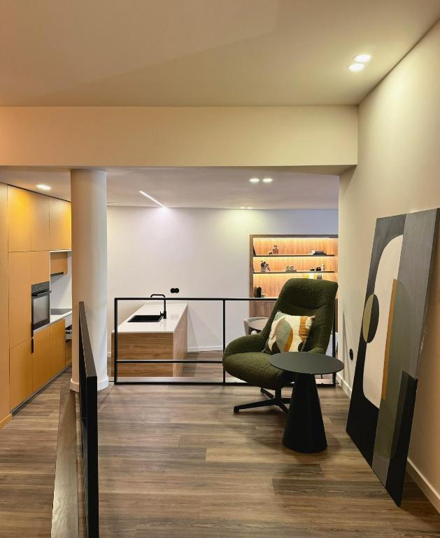 a living room with a green chair and a table at Apartamento do Ferreiro in Ponte da Barca