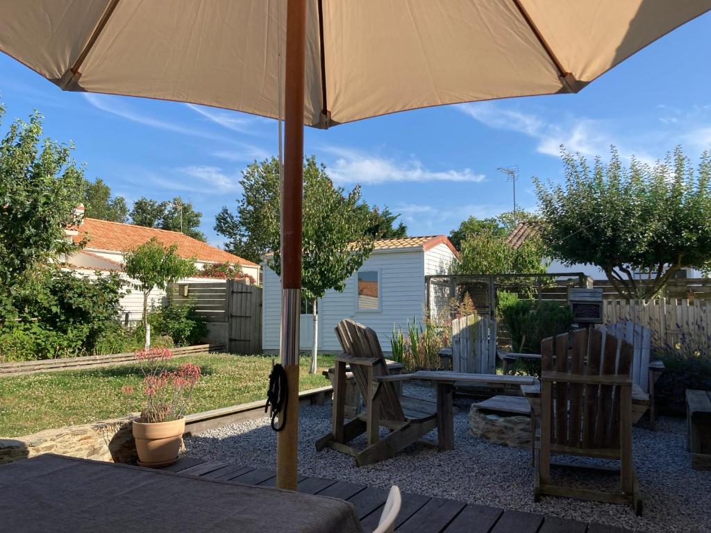 un patio avec une table, des chaises et un parasol dans l'établissement La maison de Nico et Amandine, à Commequiers