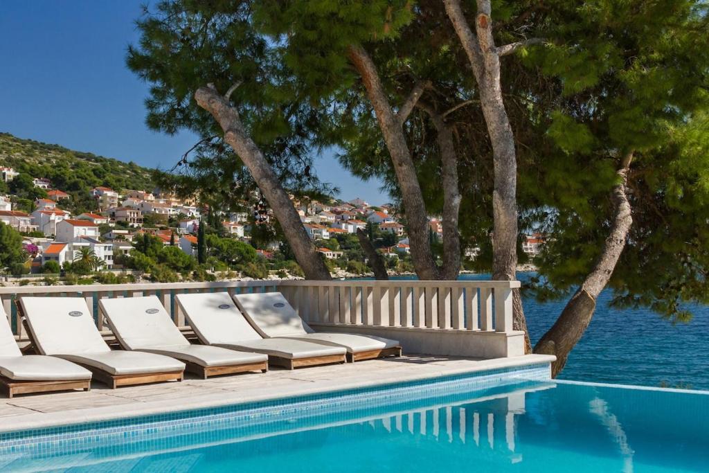 una fila di sedie a sdraio accanto alla piscina di Seafront Villa - with heated swimming pool a Trogir