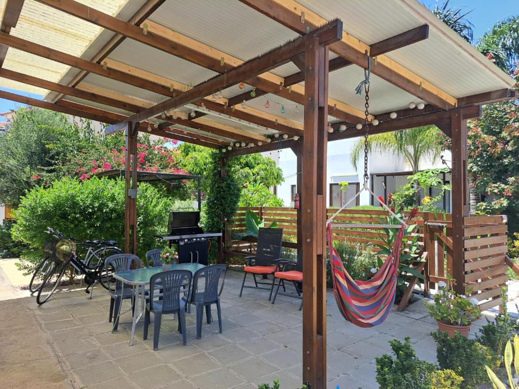 a wooden pavilion with tables and chairs and a hammock at House Near The Beach (Militsa & Aggeliki) in Pervolia