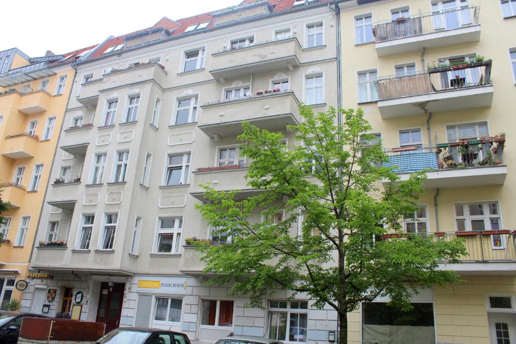 Un alto edificio bianco con un albero davanti di Pension Central Hostel Berlin a Berlino