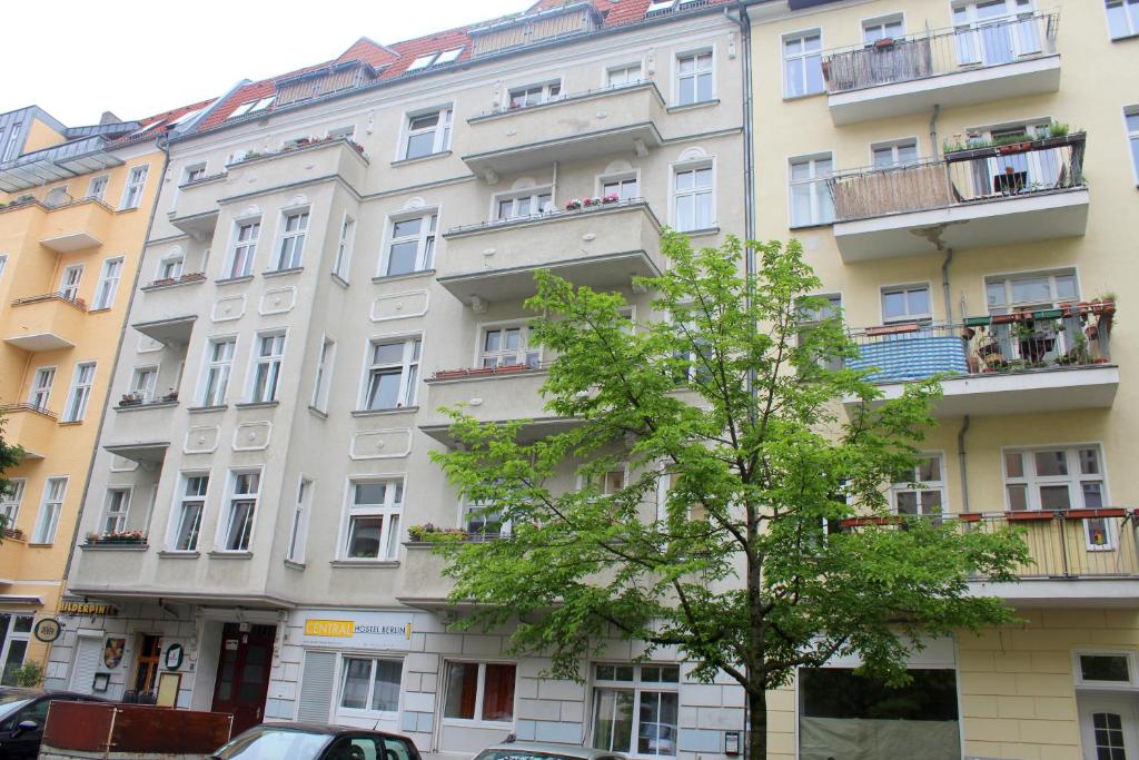 ein hohes weißes Gebäude mit einem Baum davor in der Unterkunft Pension Central Hostel Berlin in Berlin