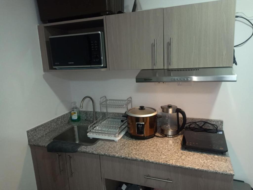 a kitchen counter with a sink and a microwave at Luxury Budget one Bedroom with living room and Kitchen Rest and fly at Amani Grand Resort in Pusok