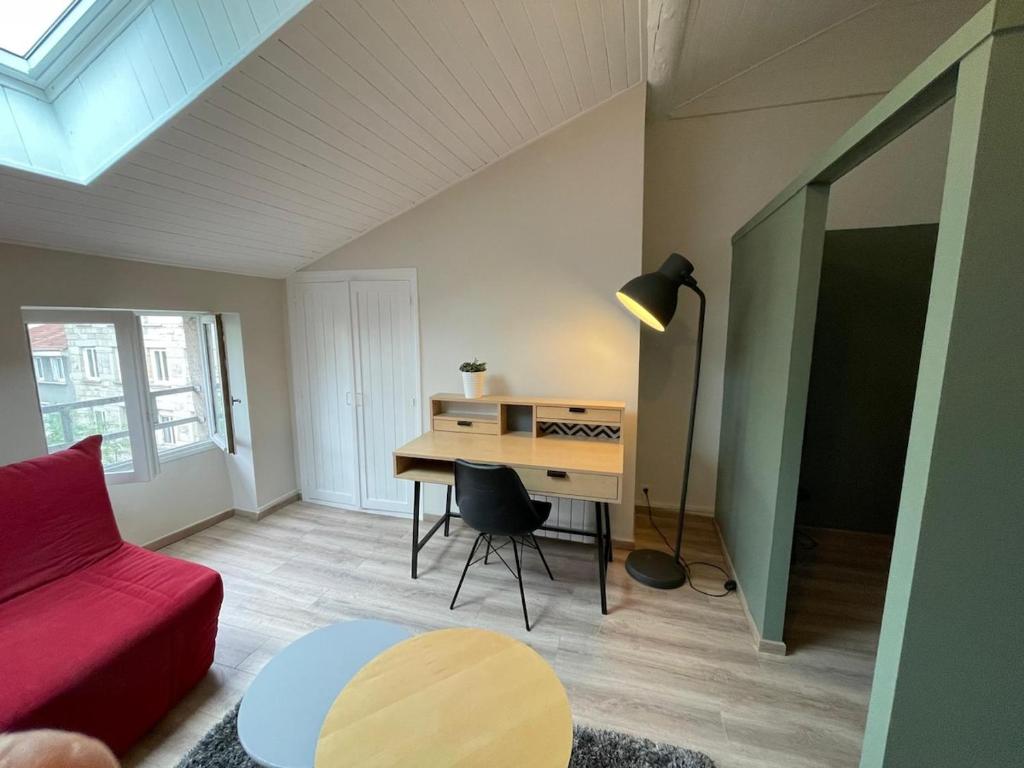 ein Wohnzimmer mit einem Schreibtisch und einem roten Sofa in der Unterkunft Nid Douillet Sous Les Toits - Calme et Cosy in Saint-Étienne