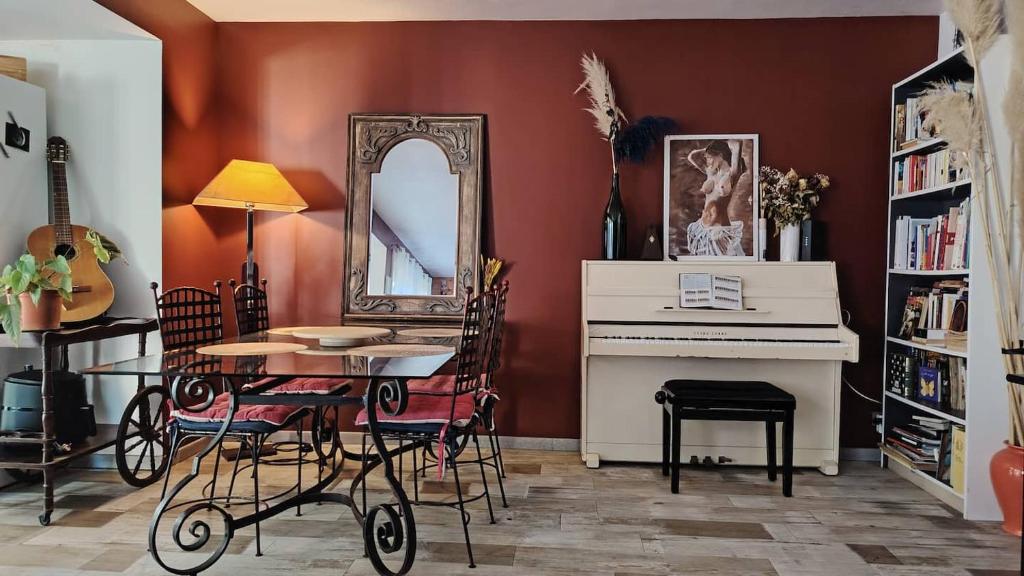 - une salle à manger avec une table, un miroir et un piano dans l'établissement De plain pied, à Sète