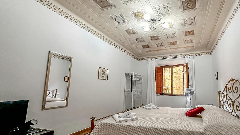 a white bedroom with a bed and a mirror at Casa di Olga - Historical Apartment inside the Walls in Lucca