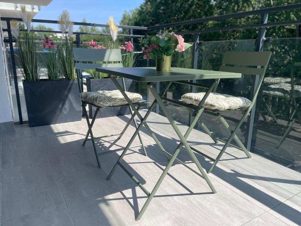 a table and two chairs with flowers on a patio at Apartament Zielona Dzielnica in Gliwice