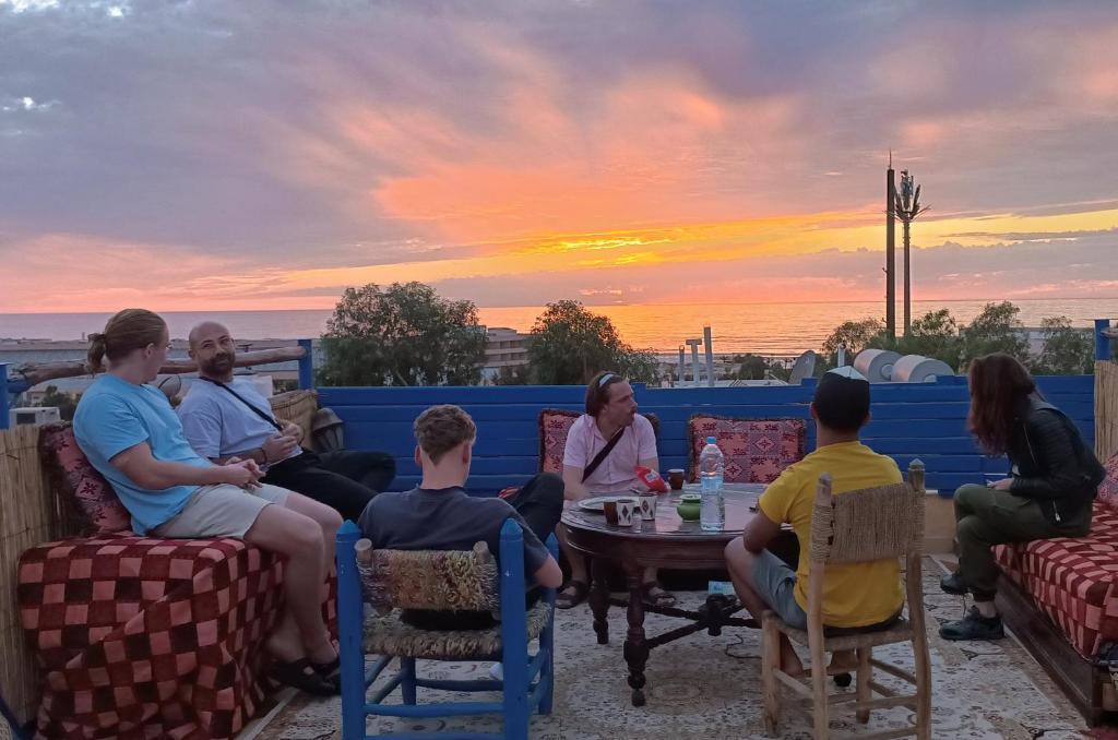 a group of people sitting around a table watching the sunset at Freebird Surfcamp Morocco in Agadir